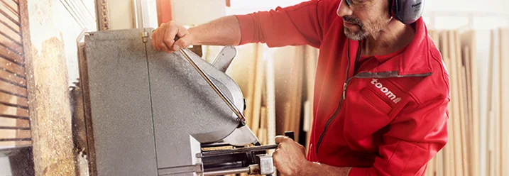 Person arbeitet mit einer Tischkreissäge an Holz.